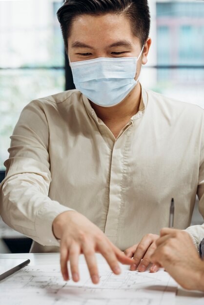 Geschäftsmann, der medizinische Masken bei der Arbeit trägt