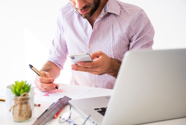 Geschäftsmann, der mit einem Handy und einem Laptop arbeitet