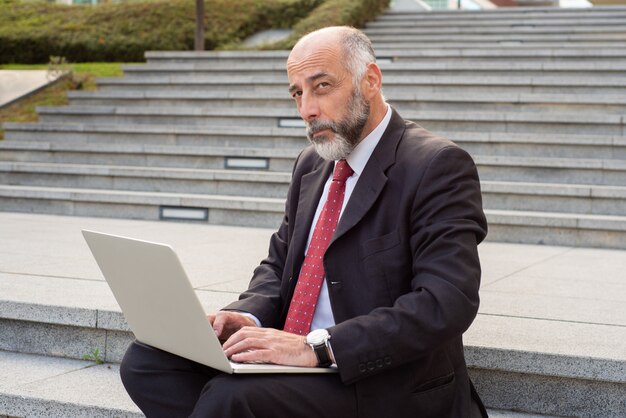 Geschäftsmann, der mit Laptop-Computer auf Straße arbeitet