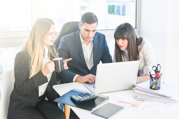 Geschäftsmann, der mit zwei Frauen arbeiten im Büro sitzt