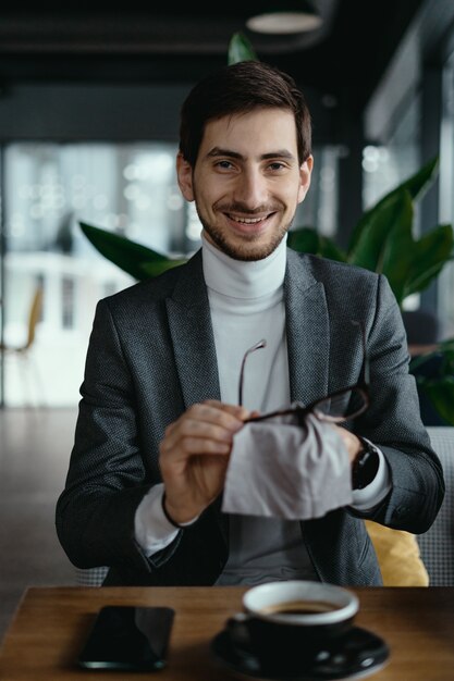 Geschäftsmann, der seine Gläser mit einer Tasse Kaffee reinigt