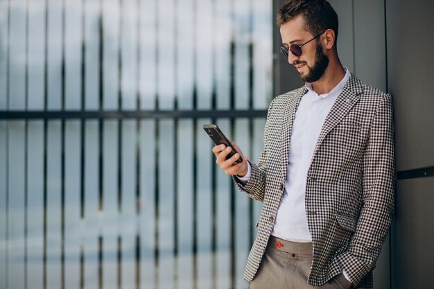 Geschäftsmann, der Telefon außerhalb des Bürozentrums benutzt