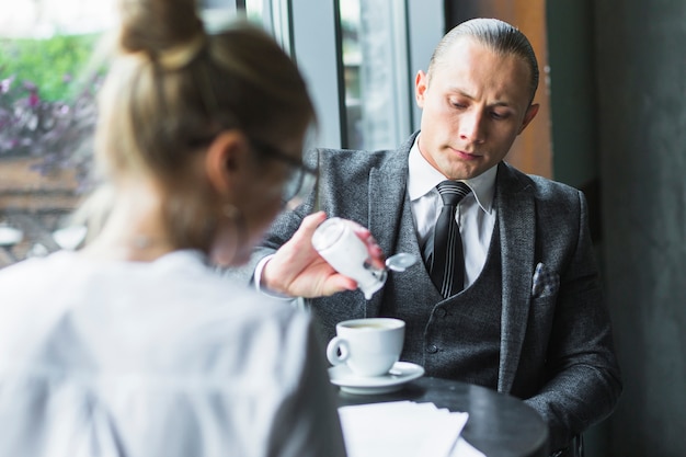 Geschäftsmann, der Zucker im Kaffee hinzufügt