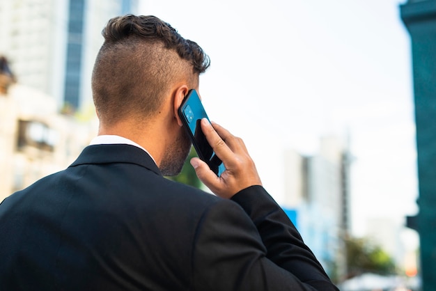 Geschäftsmann draußen, der vom hinteren Schuss am Telefon spricht