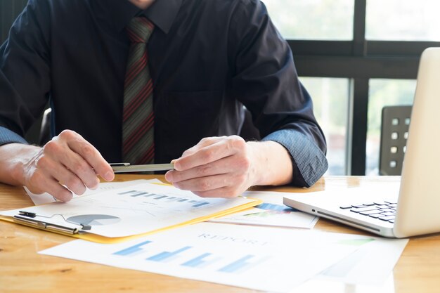 Geschäftsmann hält Stift analysieren Investition Charts mit Laptop.