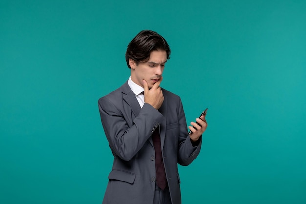 Geschäftsmann, hübscher junger brünetter Kerl im grauen Büroanzug und Krawatte, der am Telefon denkt und schaut