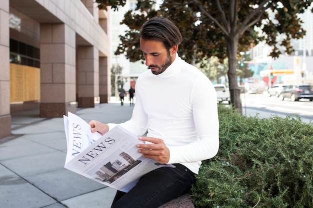 Geschäftsmann im rollkragenpullover liest zeitung in der stadt