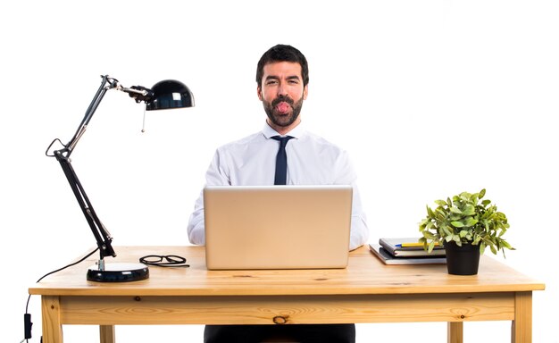 Geschäftsmann in seinem Büro, der seine Zunge herauszieht