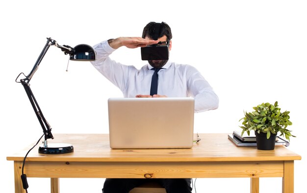 Geschäftsmann in seinem Büro mit VR Brillen halten etwas