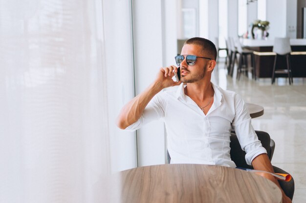 Geschäftsmann mit dem Telefon, das am Tisch sitzt