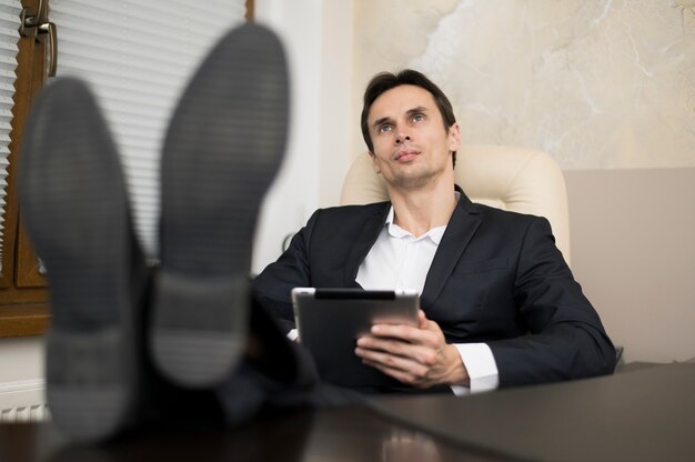 Geschäftsmann mit den Beinen auf Schreibtisch im Büro