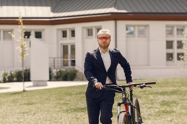 Geschäftsmann mit Fahrrad in einer Sommerstadt