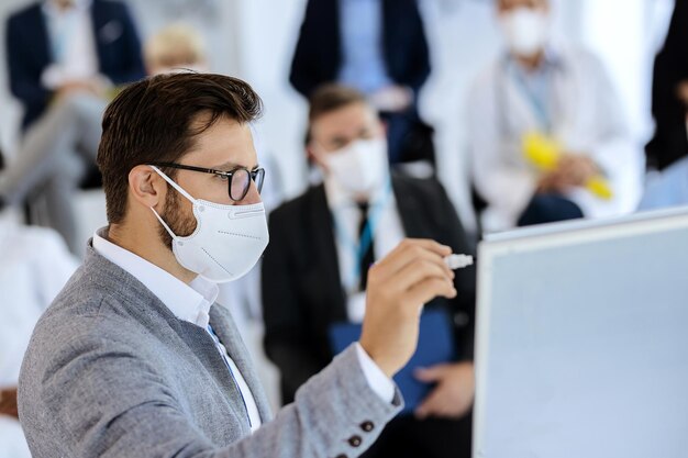 Geschäftsmann mit Gesichtsmaske, während er eine Präsentation im Sitzungssaal hält
