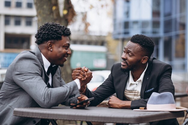 Geschäftsmann mit zwei Afrikanern, der außerhalb des Cafés sitzt