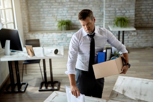 Kostenloses Foto geschäftsmann mittleren alters, der seine sachen hält und traurig ist, weil er seinen job verloren hat