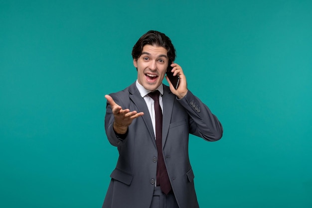 Geschäftsmann netter junger gutaussehender Mann im grauen Büroanzug und Krawatte glücklich am Telefon sprechen