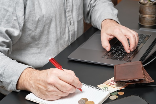 Geschäftsmann oder Buchhalter, der Stift hält, der am Schreibtisch unter Verwendung eines Laptops arbeitet, um Finanzbericht zu berechnen