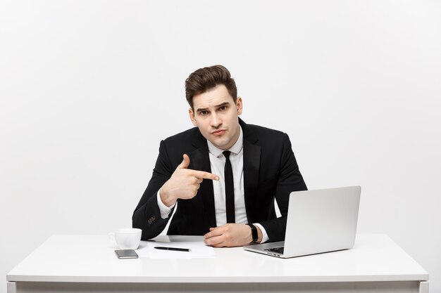 Geschäftsmann sitzt am Schreibtisch und zeigt mit dem Finger auf isolierten Laptop-Bildschirm.