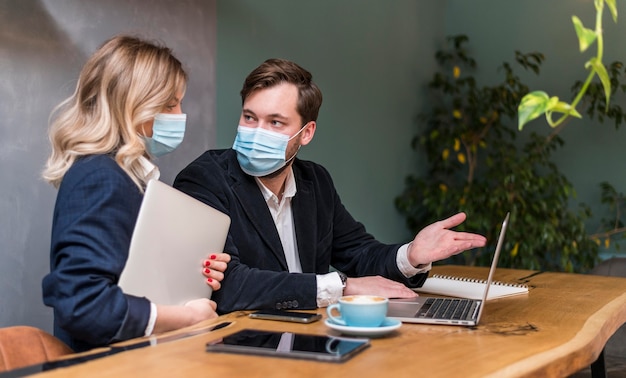 Geschäftsmann und Geschäftsfrau sprechen über ein neues Projekt, während sie medizinische Masken tragen