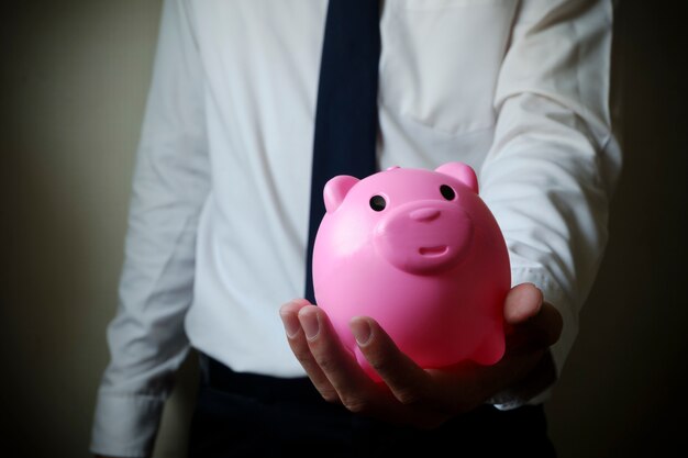 Geschäftsmann zeigt Sparschwein, Business Finance Konzept