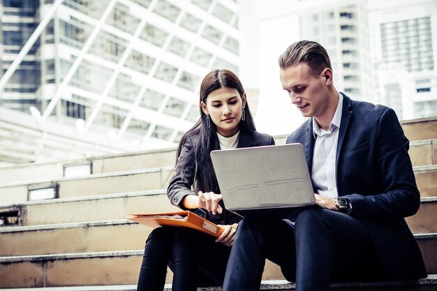 Geschäftsmitarbeiter, die neue Ideen besprechen und auf dem Laptop sitzend auf Treppenhausbüro Brainstorming sind