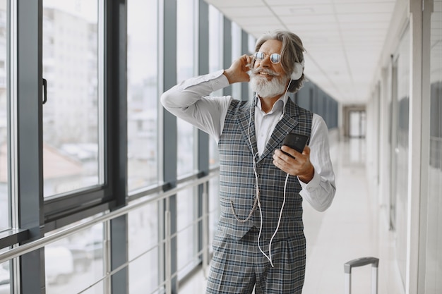 Geschäftsreise. Unternehmens- und Personenkonzept. Männchen im grauen Anzug. Senior mit Telefon und Kopfhörer.