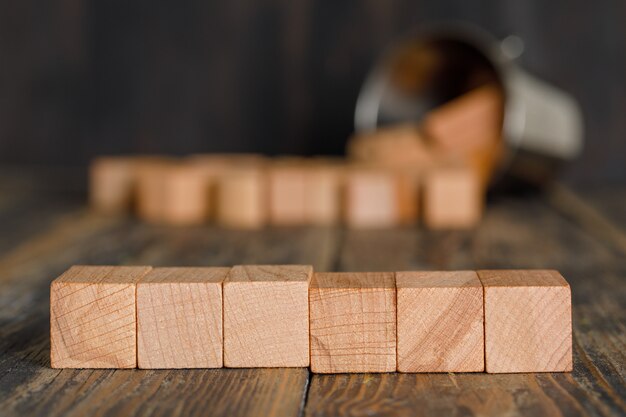Geschäftsstrategiekonzept mit verstreuten Holzwürfeln vom Eimer auf Holztischseitenansicht.