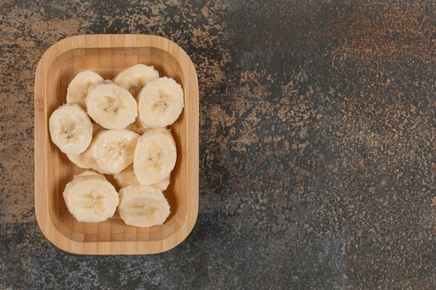 Geschälte Bananen in Scheiben geschnitten auf Holzteller.