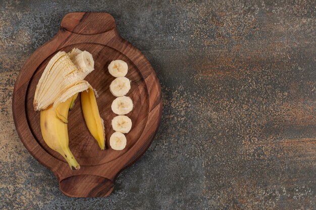 Geschälte und geschnittene Banane auf Holzbrett