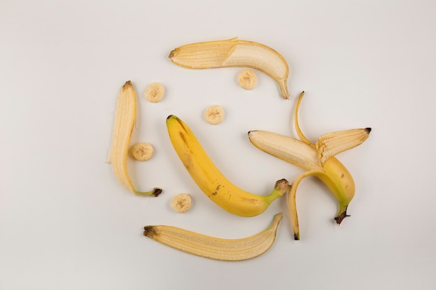 Geschälte und geschnittene Bananen auf weißem Hintergrund, Draufsicht