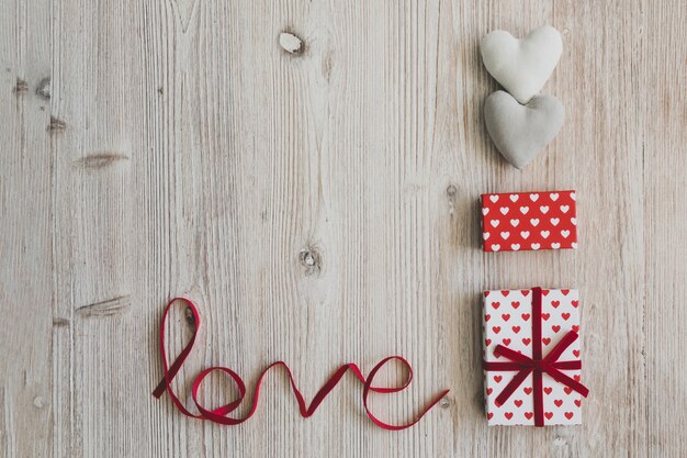 Geschenk-Boxen, zwei Herzen und das Wort &quot;Liebe&quot; auf einem Holztisch