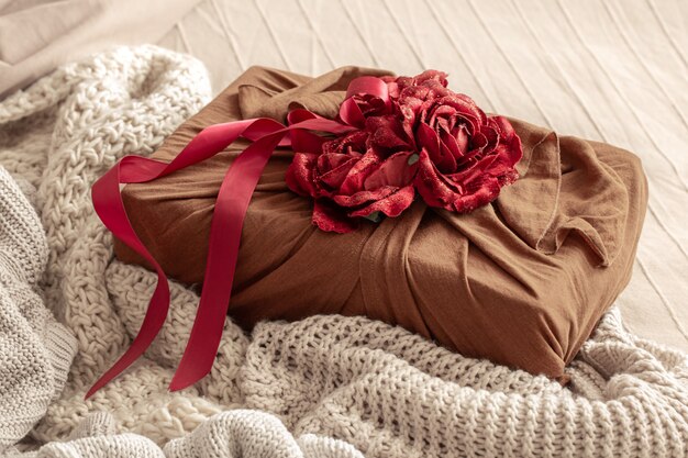 Geschenkbox mit Bändern und dekorativen Rosen auf Strickwaren. Ursprüngliche Geschenkverpackung für Valentinstag.