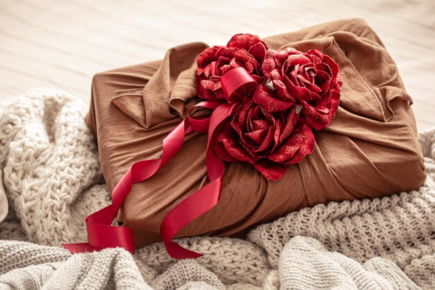 Geschenkbox mit Bändern und dekorativen Rosen auf Strickwaren. Ursprüngliche Geschenkverpackung für Valentinstag.