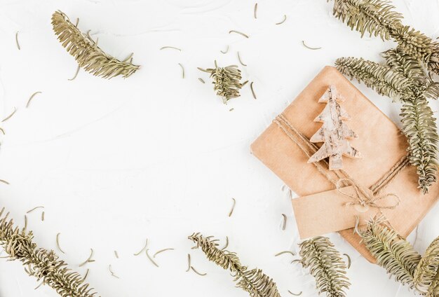 Geschenkbox mit dekorativem Tannenbaum und Tag nahe Nadelzweigen