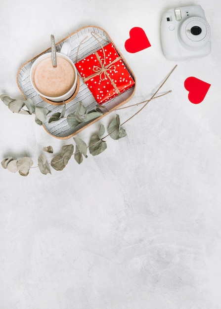 Kostenloses Foto geschenkbox und tasse getränk auf tablett in der nähe von ornament herzen, betriebszweigen und kamera