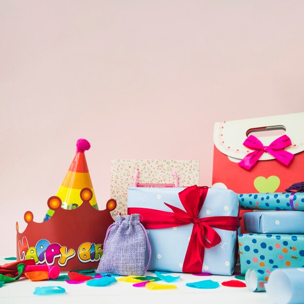 Geschenkboxen mit Kronen; Ballons und Einkaufstaschen gegen rosa Hintergrund