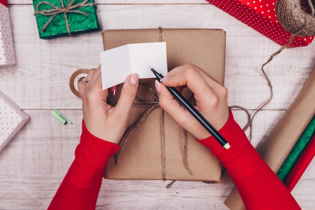 Geschenkpapier. frau packt weihnachtsgeschenke zu hause auf holztisch.