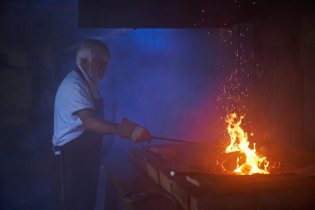 Geschickter Schmied erhitzt Stahl über brennendem Feuer