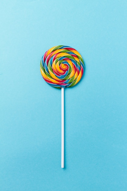 Kostenloses Foto geschmackvolle appetitliche party zubehör sweet swirl süßigkeiten lollypop auf blauem hintergrund draufsicht