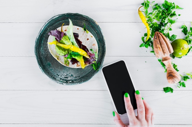 Geschmackvolle mexikanische Burritos mit Smartphone