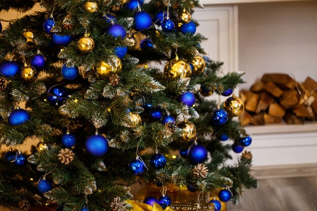 Geschmückter weihnachtsbaum nahaufnahme. blaue und goldene kugeln und