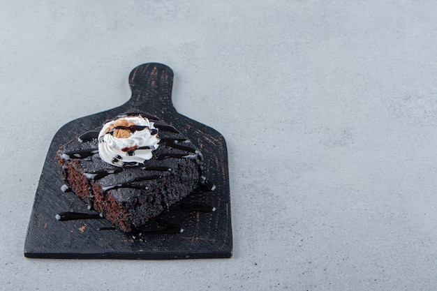 Geschnitten von leckerem Schokoladenbrownie mit Sahne auf Schneidebrett. Foto in hoher Qualität