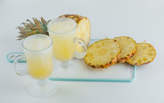 Geschnittene Ananas mit Säften auf Schneidebrett