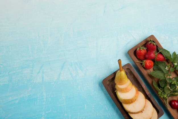 Geschnittene Birnen mit Erdbeeren und anderen Beeren in Holzplatten in der Ecke