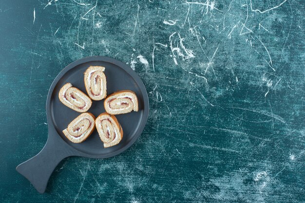 Geschnittene Brötchenkuchen auf einer Pfanne, auf der blauen Oberfläche