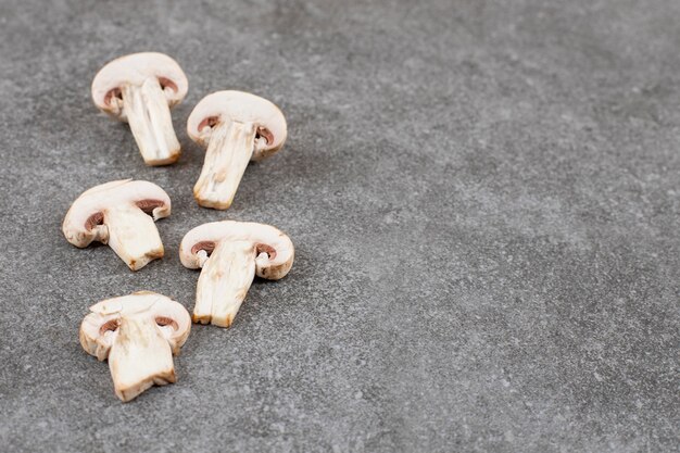 Geschnittene frische Pilze auf grauem Tisch.