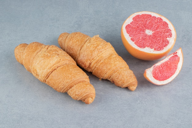 Geschnittene Grapefruit und Croissant auf dem Marmorhintergrund. Hochwertiges Foto