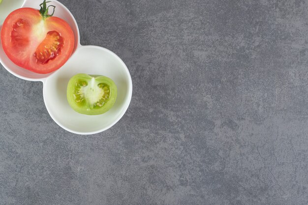 Geschnittene grüne und rote Tomaten auf weißem Teller. Foto in hoher Qualität