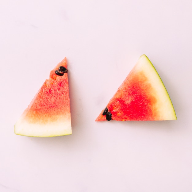 Geschnittene helle Wassermelone gesetzt auf rosa Oberfläche