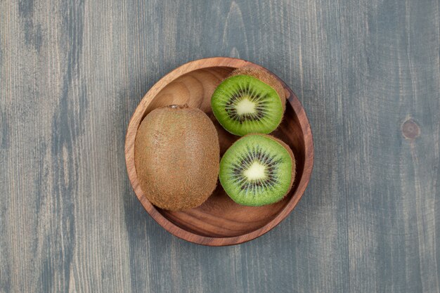 Geschnittene Kiwi mit ganzer Kiwi auf einem Holztisch